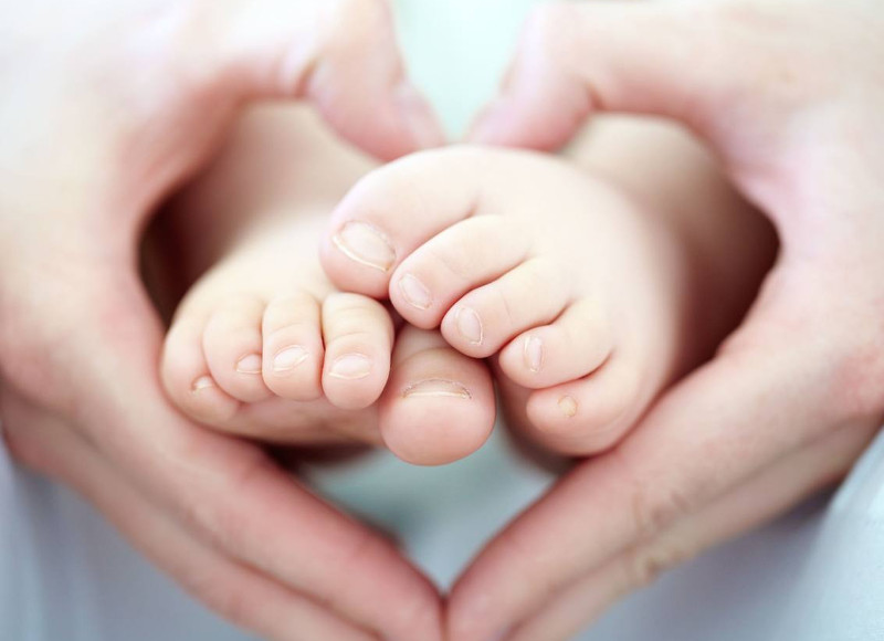 A baby girls feet being held the heart-shaped hands of her motherTFGP.